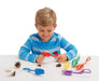 Child smiling and playing with Tickit Fine Motor Tongs